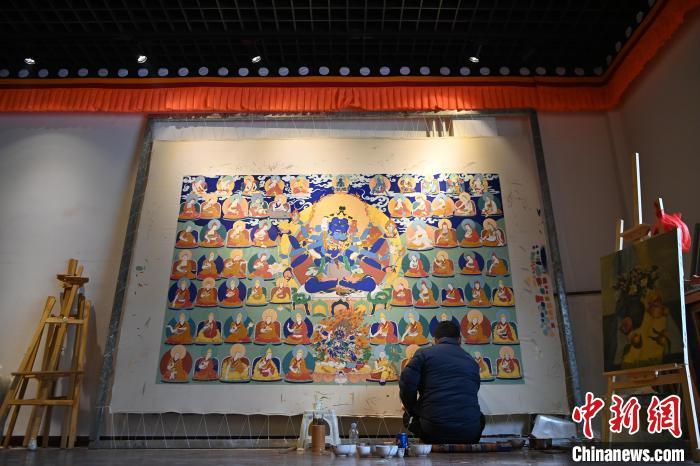 圖為青年畫師旦正嘉在唐卡小鎮(zhèn)一畫室內席地而坐繪制巨幅唐卡。作為唐卡文化的傳承人，交巴加布致力于培養(yǎng)新一代唐卡畫師，將自己的藝術經驗和技藝毫無保留地傳授給學生們。自1997年以來，交巴加布收徒數(shù)十名，傳授唐卡畫法。九美旦增 攝

