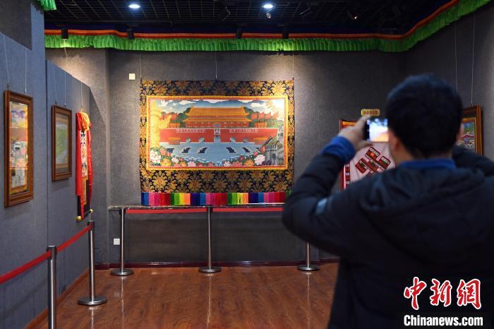 圖為游客在唐卡小鎮(zhèn)一展廳內參觀展出的唐卡作品。九美旦增 攝