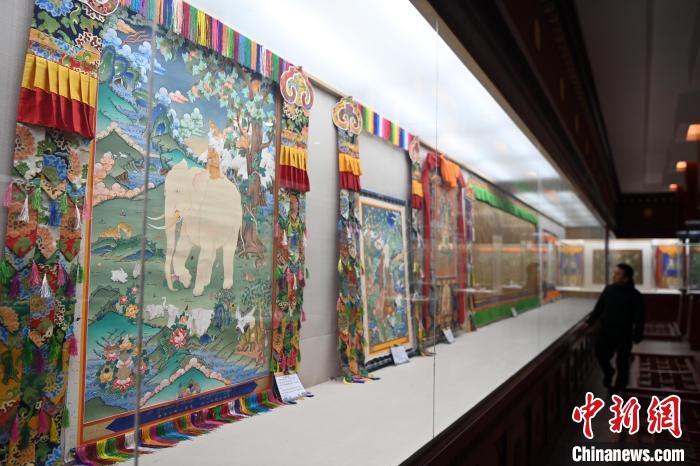 距離唐卡小鎮(zhèn)數(shù)十米遠的精品唐卡展廳，擺滿了甘南藏族唐卡國家級代表性傳承人交巴加布與父親二人的作品。圖為交巴加布與父親的唐卡作品吸引游人“打卡”。九美旦增 攝

